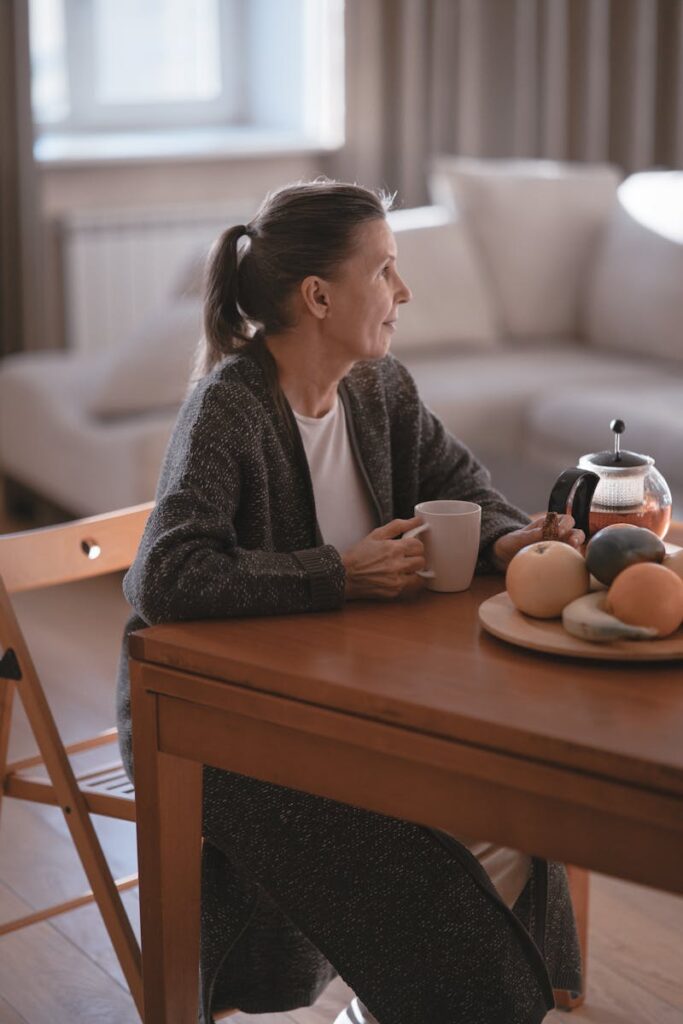 Como lidar com a sogra: Senior woman enjoying coffee in a cozy home setting, reflecting a peaceful and relaxed moment of leisure.